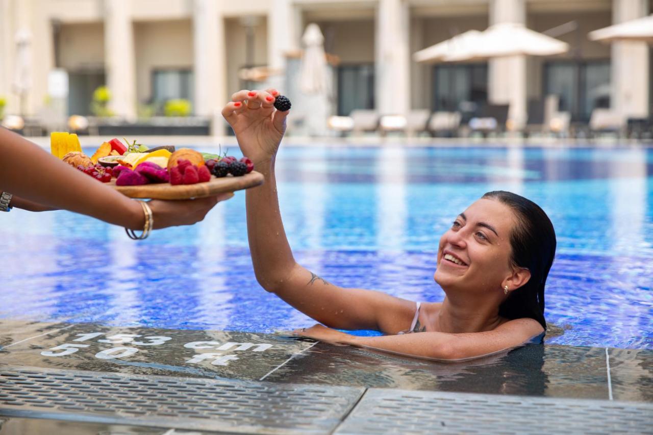 Triumph Luxury Hotel Cairo Exterior photo A woman being served fruit in a swimming pool